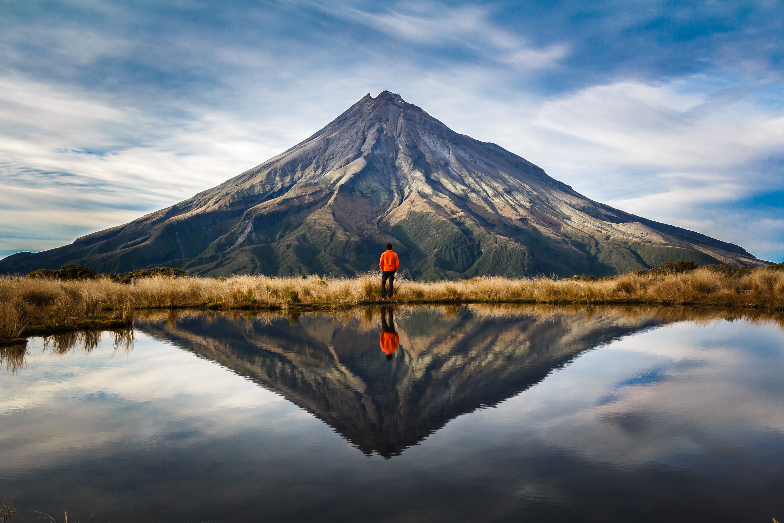 mountaineer-looking-at-volcano-with-perfect-symmetric-reflection